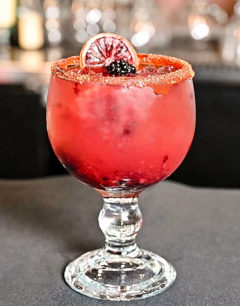Fresh blackberry margarita in a stemmed glass with a chile-salt rim and blackberry garnish